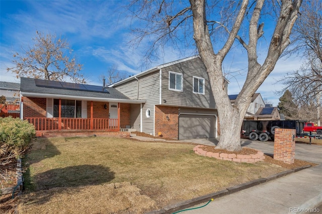 split level home with solar panels, a porch, a garage, and a front yard