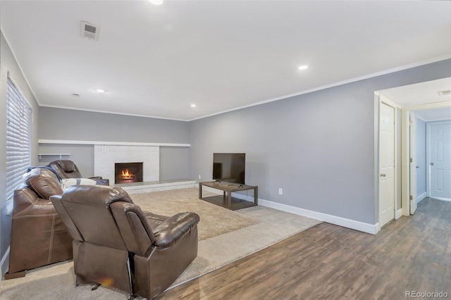 living room featuring wood-type flooring, a fireplace, and ornamental molding