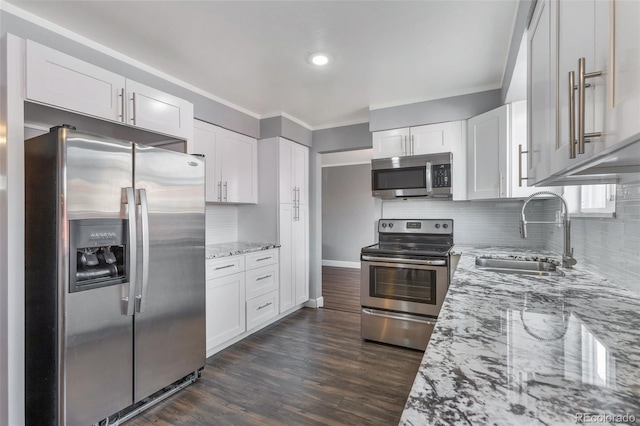 kitchen featuring appliances with stainless steel finishes, light stone counters, white cabinetry, and sink