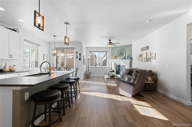 kitchen featuring white cabinetry, hanging light fixtures, dark hardwood / wood-style floors, and sink