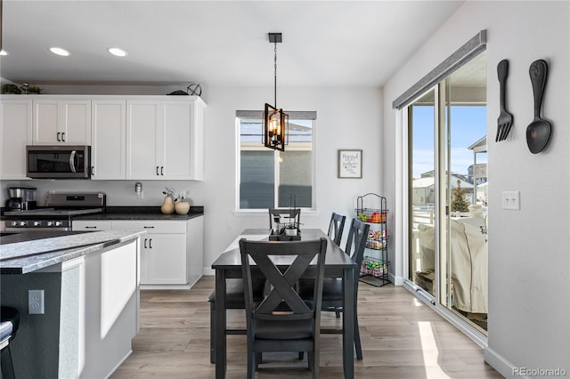 kitchen featuring pendant lighting, stainless steel appliances, white cabinets, a chandelier, and light wood-type flooring