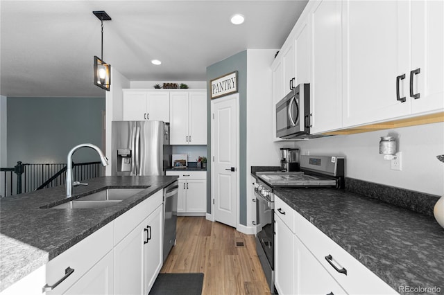 kitchen featuring stainless steel appliances, sink, hanging light fixtures, and white cabinets