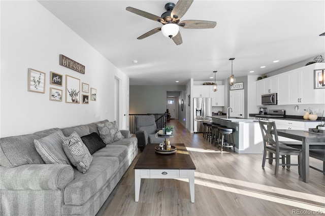 living room featuring sink, wood-type flooring, and ceiling fan