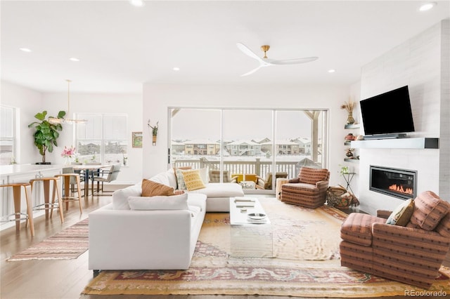 living area with a fireplace, recessed lighting, wood finished floors, and ceiling fan