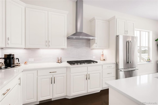 kitchen featuring stainless steel appliances, decorative backsplash, light countertops, white cabinets, and wall chimney range hood