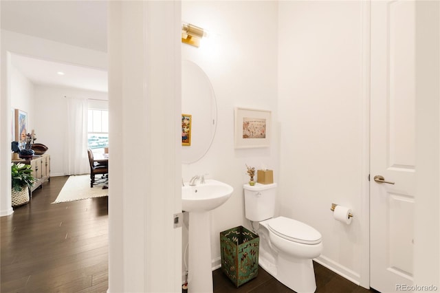 half bathroom with toilet, baseboards, and wood finished floors