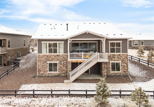 rear view of house with stairway, stone siding, and fence private yard