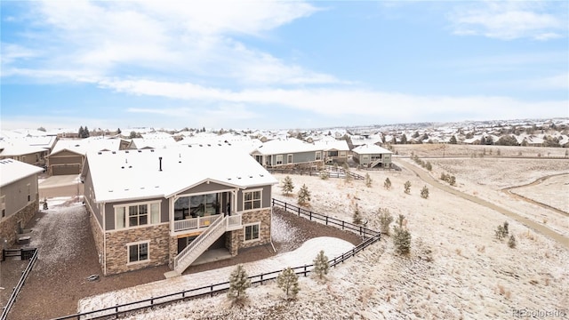 back of property featuring fence, stone siding, and a residential view