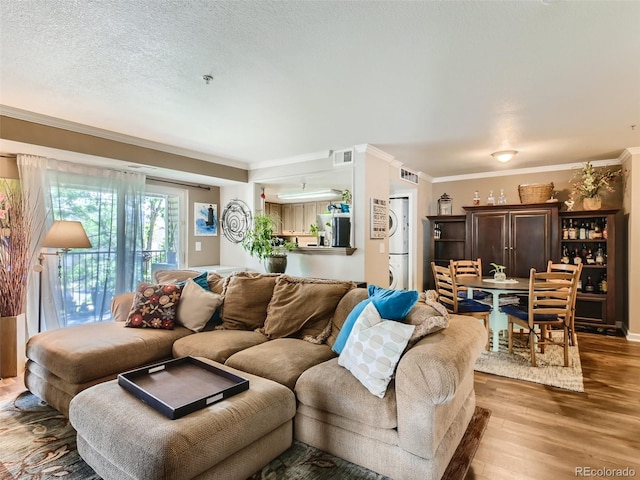 living room featuring ornamental molding, wood-type flooring, and a textured ceiling