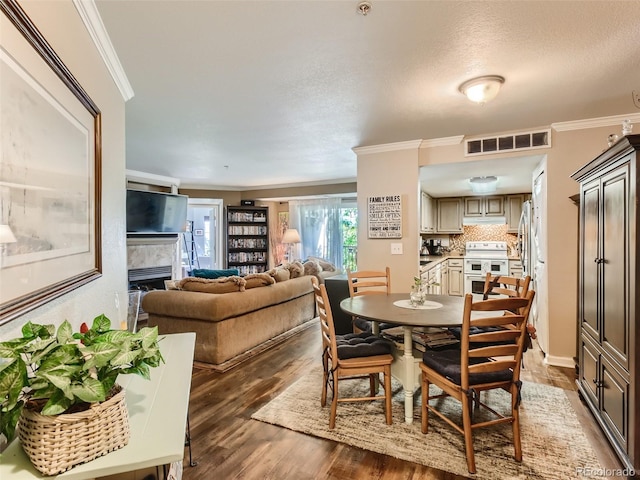 dining space featuring crown molding, a high end fireplace, dark hardwood / wood-style floors, and a textured ceiling