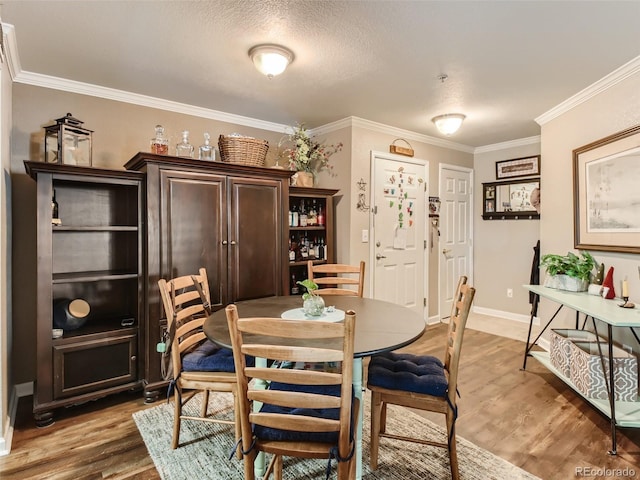 dining room with a textured ceiling, crown molding, and hardwood / wood-style floors