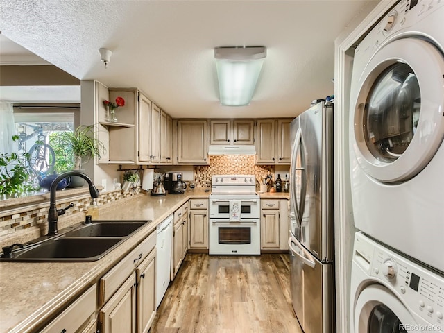 kitchen with light wood-type flooring, white appliances, sink, stacked washer and clothes dryer, and light brown cabinetry