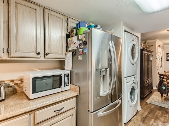 laundry area featuring crown molding, dark hardwood / wood-style flooring, and stacked washing maching and dryer