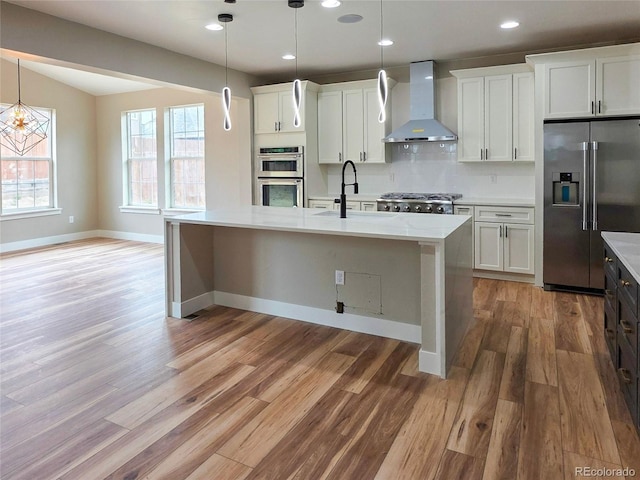 5550 Wetlands Dr, Longmont, CO 80504 - kitchen with appliances with stainless steel finishes, wall chimney range hood, light wood-type flooring, an island with sink, and recessed lighting