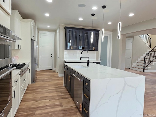 5550 Wetlands Dr, Longmont, CO 80504 - kitchen featuring light wood-type flooring, stainless steel appliances, glass insert cabinets, white cabinetry, and recessed lighting