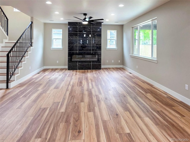 5550 Wetlands Dr, Longmont, CO 80504 - unfurnished living room featuring wood finished floors, stairway, ceiling fan, recessed lighting, and a fireplace