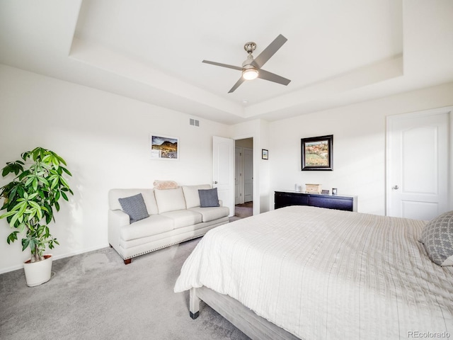 bedroom featuring a raised ceiling, carpet flooring, ceiling fan, and visible vents