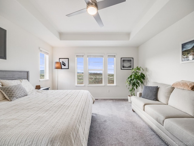 carpeted bedroom with baseboards, a ceiling fan, and a raised ceiling