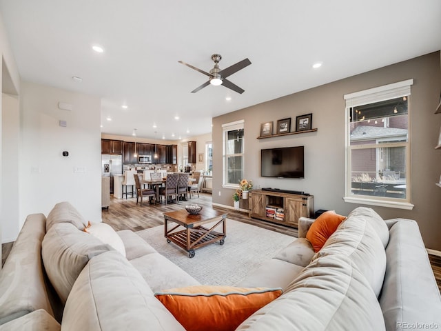 living area with light wood-style flooring, recessed lighting, ceiling fan, and baseboards