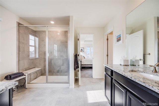 full bath with ensuite bathroom, a shower stall, vanity, tile patterned floors, and baseboards