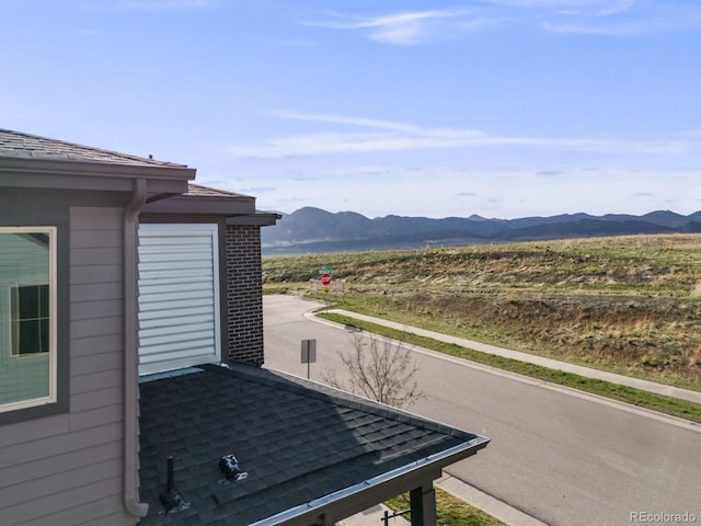 exterior space with a mountain view, a downspout, and gutters