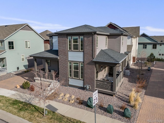 view of front facade with a patio, cooling unit, a residential view, and roof with shingles