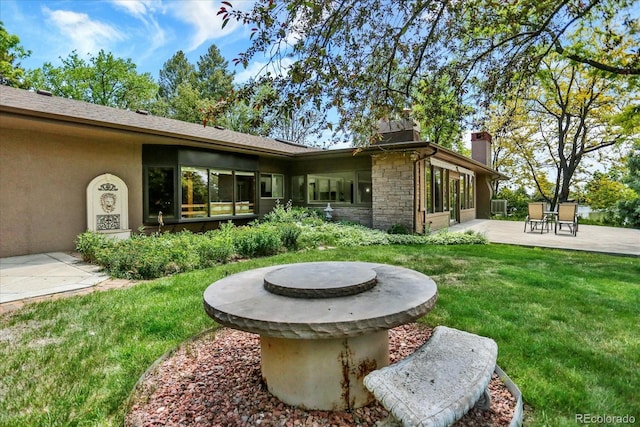 4790 W Lakeridge Rd, Denver, CO 80219 - rear view of property featuring a patio area, a yard, a chimney, stucco siding, and stone siding