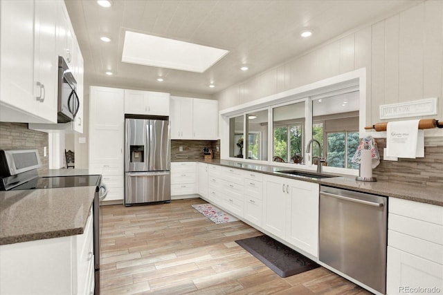 4790 W Lakeridge Rd, Denver, CO 80219 - kitchen featuring appliances with stainless steel finishes, a sink, a skylight, tasteful backsplash, and white cabinets