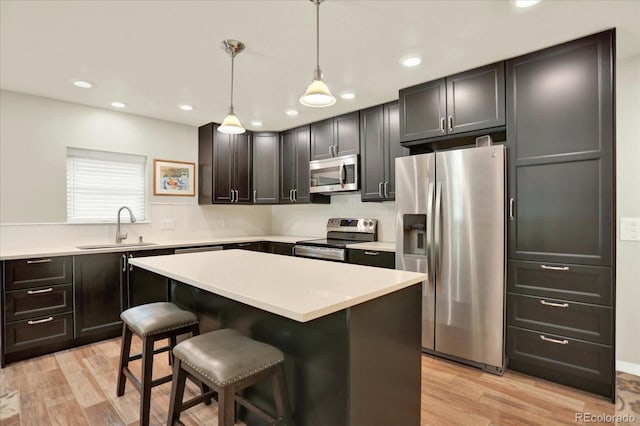 4790 W Lakeridge Rd, Denver, CO 80219 - kitchen with appliances with stainless steel finishes, a sink, light wood-style flooring, a breakfast bar, and recessed lighting