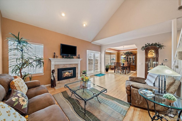 living room with high vaulted ceiling, a fireplace, and light wood-type flooring