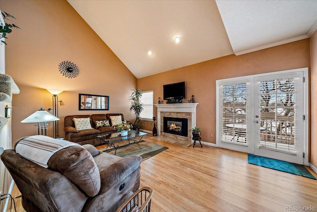 living room featuring french doors, a fireplace, high vaulted ceiling, and light hardwood / wood-style flooring