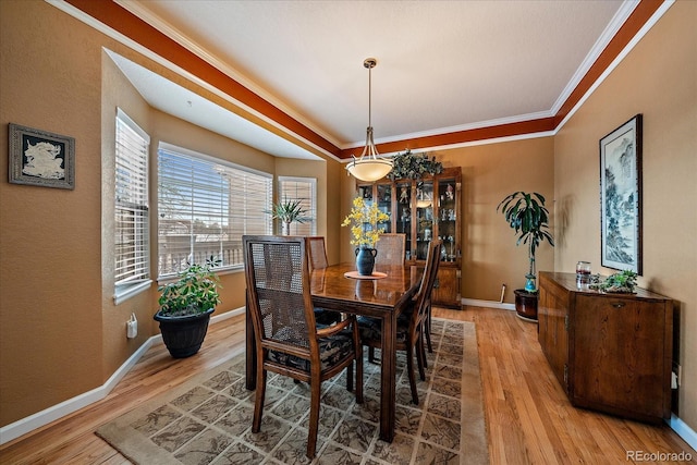 dining area with ornamental molding and light hardwood / wood-style flooring