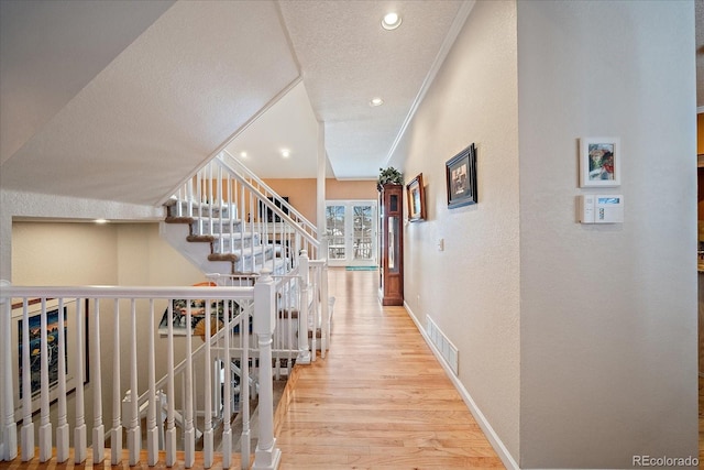 corridor with crown molding, hardwood / wood-style floors, and a textured ceiling