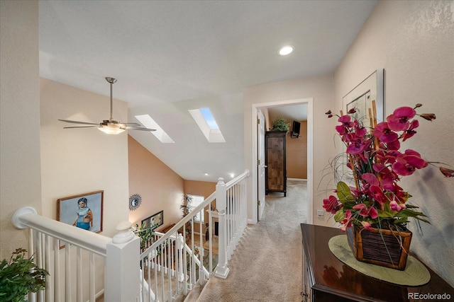 hallway featuring vaulted ceiling with skylight and light carpet