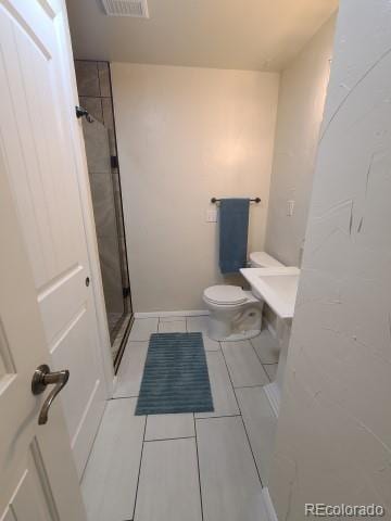 bathroom featuring a tile shower and toilet