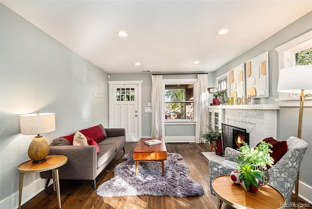 living room featuring a fireplace, dark hardwood / wood-style floors, and a healthy amount of sunlight