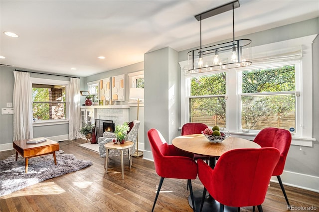 dining room featuring wood-type flooring and a brick fireplace