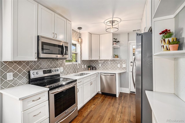 kitchen featuring hanging light fixtures, sink, white cabinets, dark hardwood / wood-style floors, and stainless steel appliances