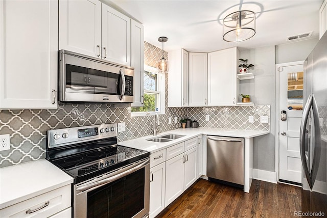 kitchen with sink, white cabinets, pendant lighting, dark wood-type flooring, and stainless steel appliances