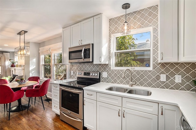 kitchen with appliances with stainless steel finishes, decorative light fixtures, white cabinetry, tasteful backsplash, and sink