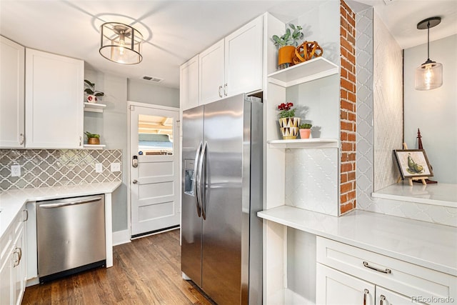 kitchen featuring hanging light fixtures, appliances with stainless steel finishes, white cabinets, dark hardwood / wood-style floors, and decorative backsplash