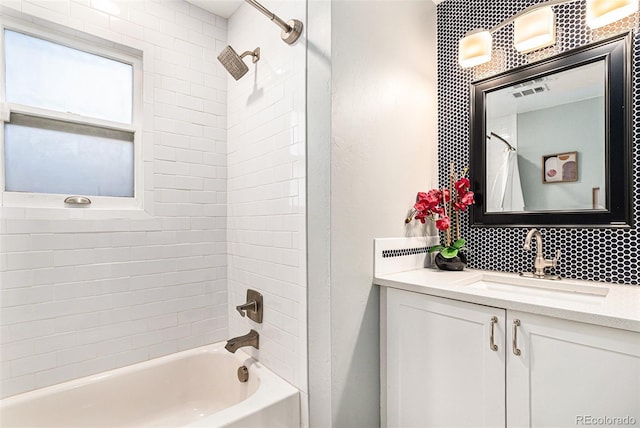 bathroom with decorative backsplash, tiled shower / bath, and vanity