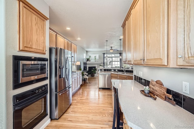 11638 Xavier Way, Westminster, CO 80031 - kitchen with appliances with stainless steel finishes, light wood-style flooring, open floor plan, a fireplace, and light stone countertops