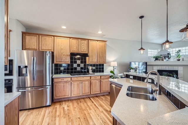 11638 Xavier Way, Westminster, CO 80031 - kitchen with appliances with stainless steel finishes, under cabinet range hood, hanging light fixtures, light wood-style floors, and recessed lighting