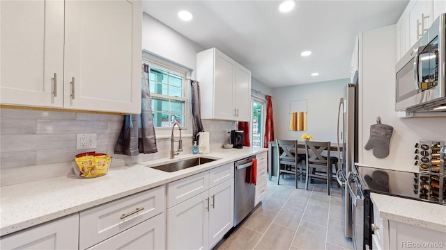 7609 Sherman Pl, Denver, CO 80221 - kitchen with sink, white cabinets, decorative backsplash, light stone counters, and stainless steel appliances