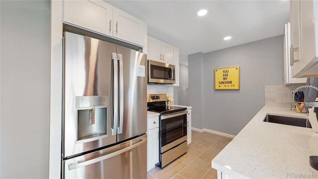 7609 Sherman Pl, Denver, CO 80221 - kitchen with sink, stainless steel appliances, light stone counters, white cabinets, and decorative backsplash