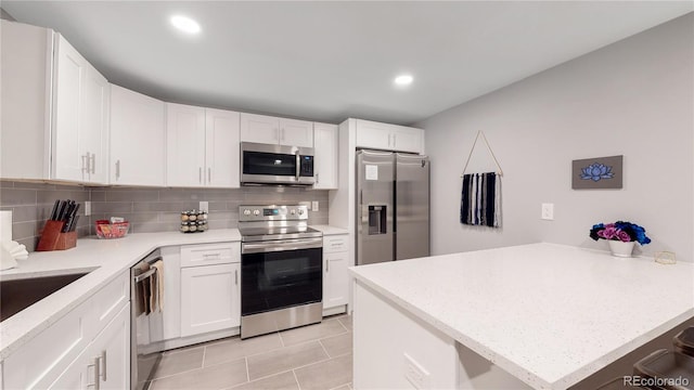 7609 Sherman Pl, Denver, CO 80221 - kitchen with stainless steel appliances, white cabinetry, light tile patterned floors, and backsplash