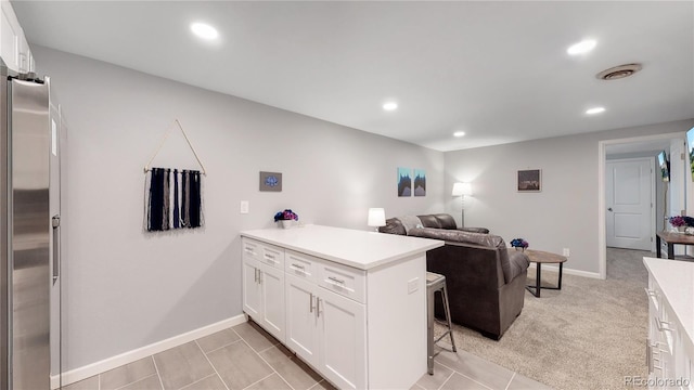 7609 Sherman Pl, Denver, CO 80221 - kitchen with a kitchen bar, light carpet, stainless steel fridge, kitchen peninsula, and white cabinets