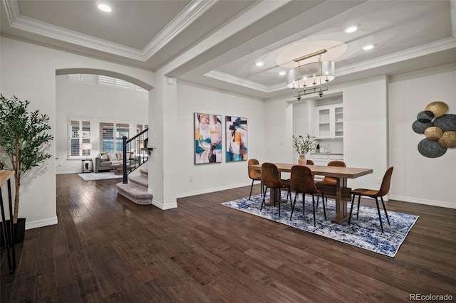 dining room featuring a raised ceiling, dark hardwood / wood-style flooring, crown molding, and an inviting chandelier