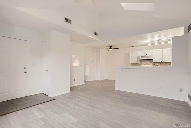 unfurnished living room with ceiling fan, light wood-type flooring, high vaulted ceiling, and a skylight